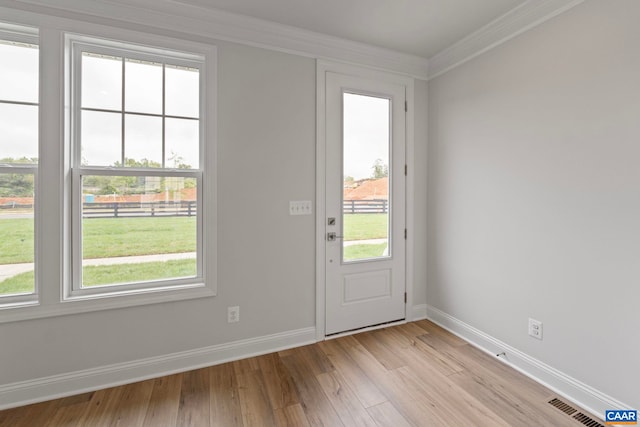 entryway with baseboards, ornamental molding, light wood finished floors, and visible vents