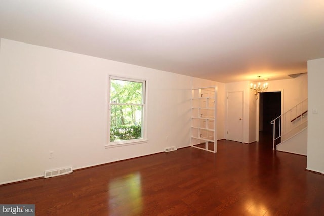  - empty room with a chandelier, wood finished floors, and baseboards