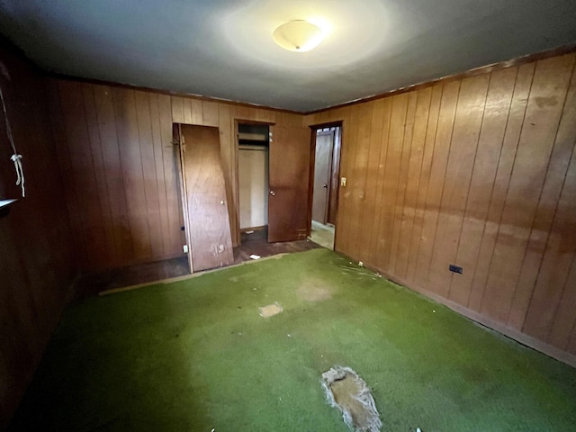 unfurnished bedroom featuring wooden walls and carpet