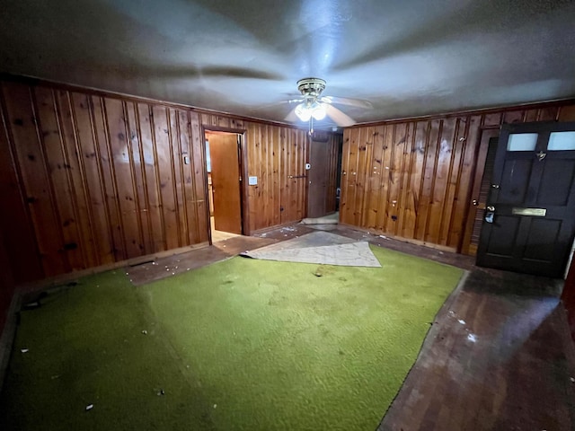 interior space with ceiling fan, wooden walls, and wood finished floors