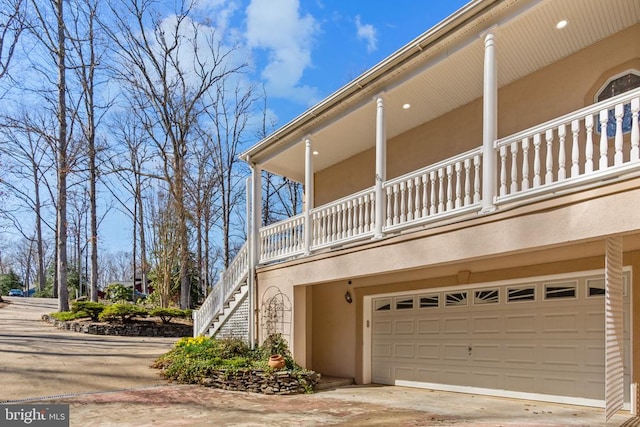view of home's exterior featuring a garage, a balcony, stucco siding, concrete driveway, and stairs