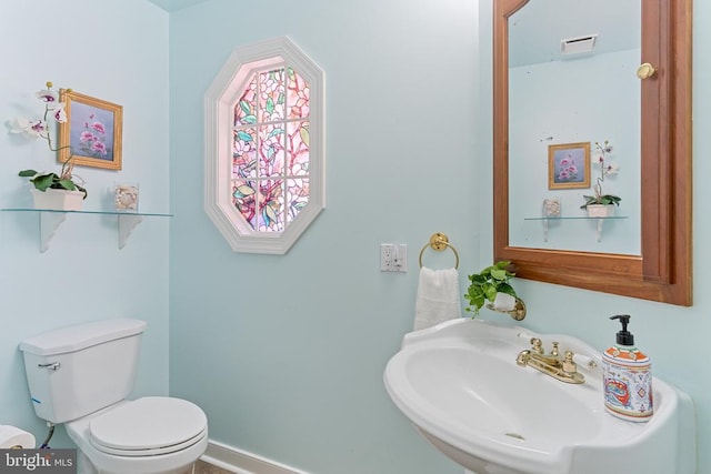half bath with a sink, toilet, and baseboards