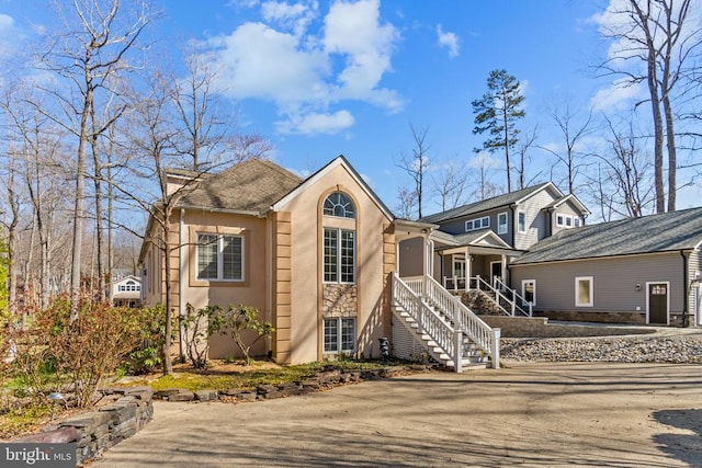 view of front of house featuring stucco siding, a porch, and stairway