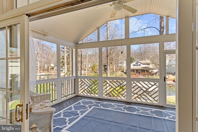 unfurnished sunroom with a ceiling fan, healthy amount of natural light, and vaulted ceiling