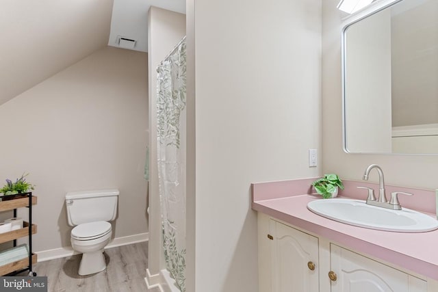 bathroom featuring wood finished floors, toilet, lofted ceiling, and vanity