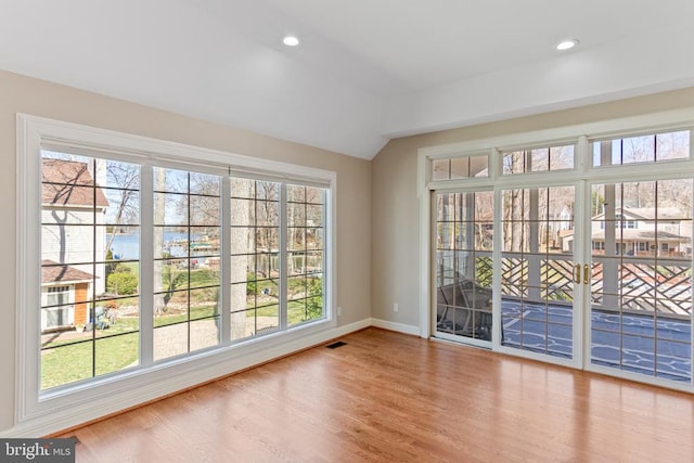 doorway to outside with wood finished floors, baseboards, healthy amount of natural light, lofted ceiling, and recessed lighting