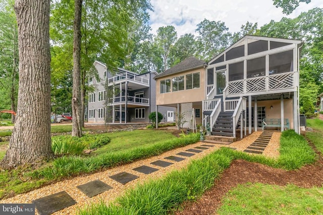back of house with a sunroom, stucco siding, and stairs