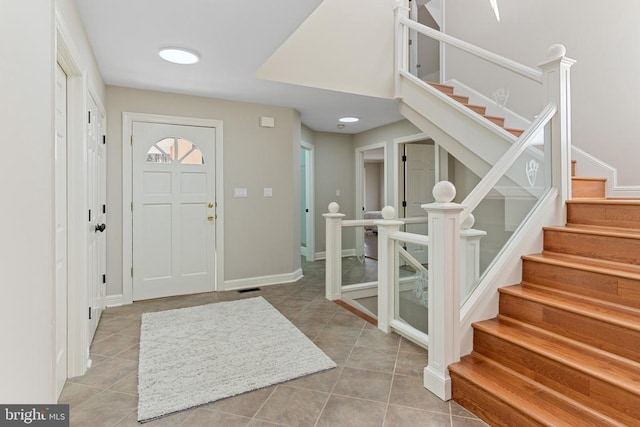 foyer featuring tile patterned flooring, stairway, and baseboards
