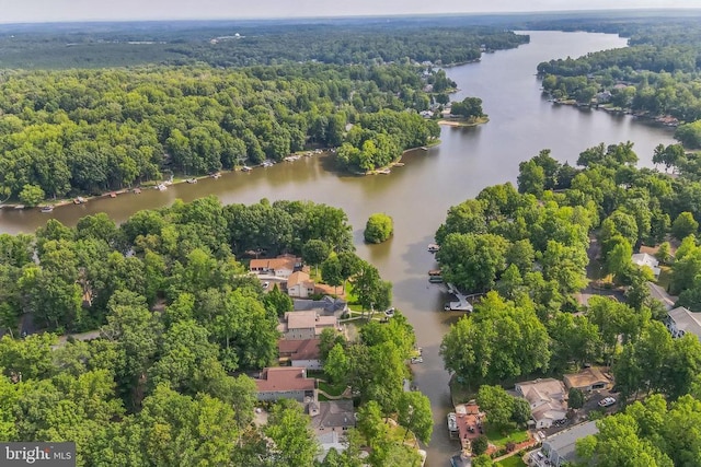 drone / aerial view of a nearby body of water and a heavily wooded area