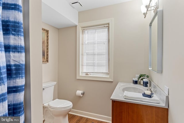 bathroom with baseboards, wood finished floors, toilet, and vanity