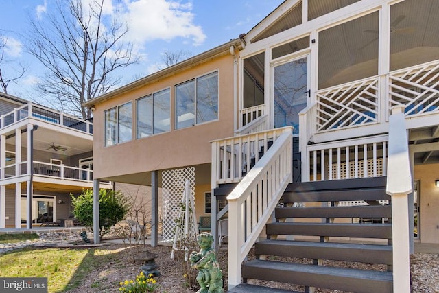 view of side of home with stairs, stucco siding, and ceiling fan