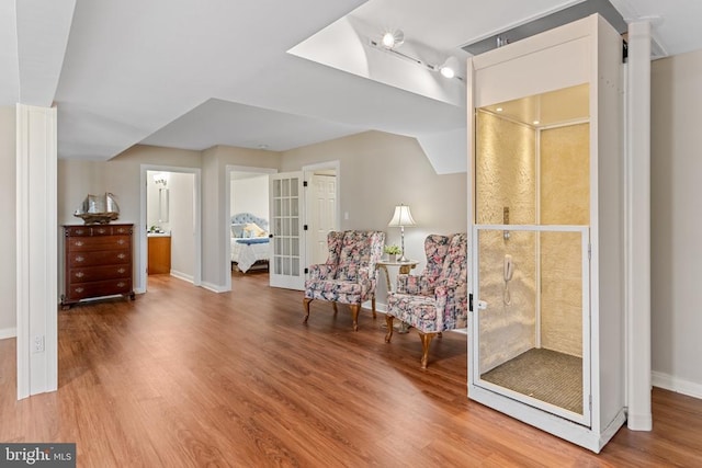 sitting room with wood finished floors, baseboards, french doors, and ornate columns