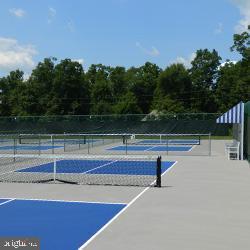 view of tennis court with community basketball court and fence
