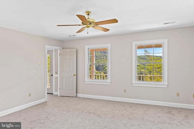 spare room with baseboards, carpet flooring, visible vents, and a healthy amount of sunlight