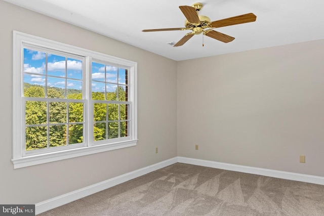 carpeted empty room featuring a ceiling fan and baseboards