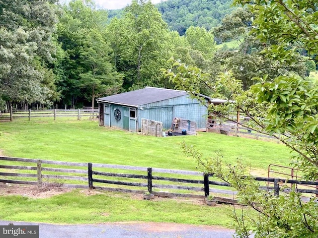 view of yard featuring an outbuilding, a rural view, and fence