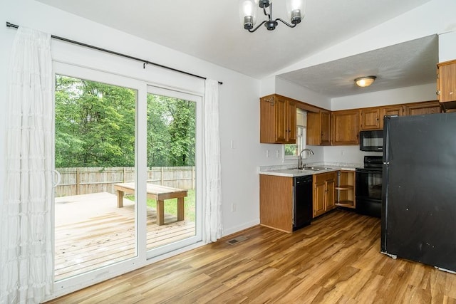 1014 Paul St, Harrisonburg, VA 22802 - kitchen featuring black appliances, light countertops, vaulted ceiling, brown cabinetry, and a chandelier