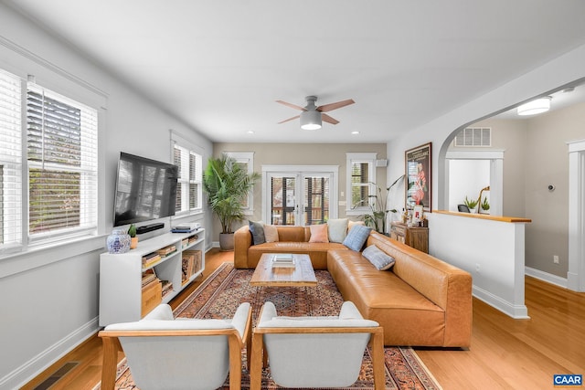 living room with light wood-type flooring, visible vents, baseboards, and a ceiling fan