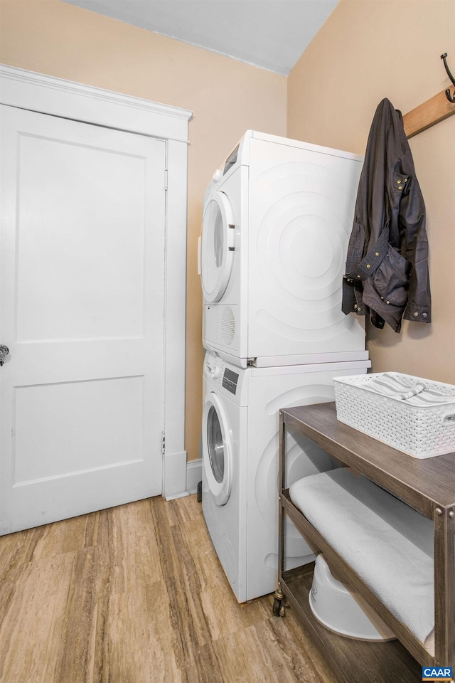 laundry area with laundry area, stacked washer and clothes dryer, and light wood-style flooring