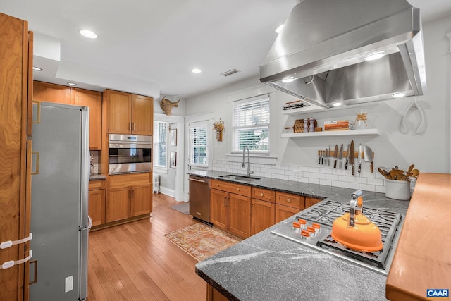 kitchen with recessed lighting, a sink, wall chimney range hood, stainless steel appliances, and tasteful backsplash