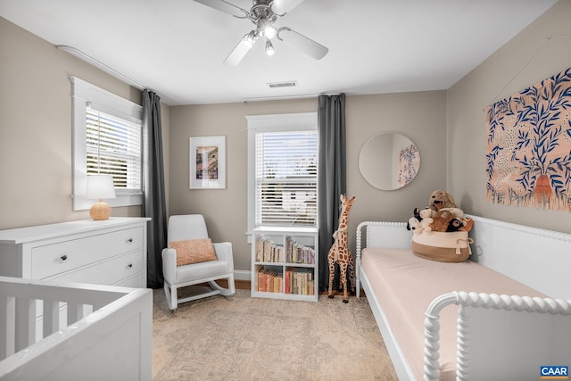 bedroom featuring a nursery area, visible vents, baseboards, and ceiling fan