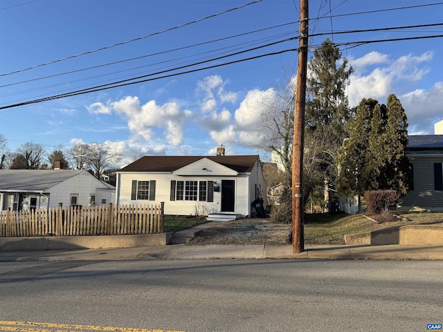 bungalow featuring a fenced front yard and a chimney