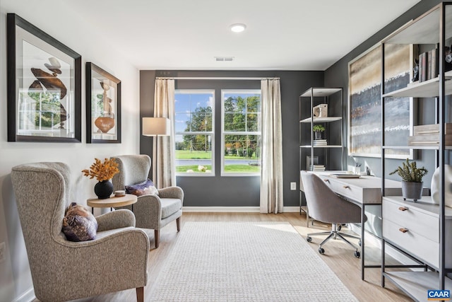 office area with built in desk, light wood finished floors, baseboards, and visible vents