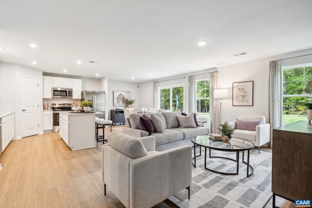 living area with recessed lighting, light wood-style floors, and visible vents