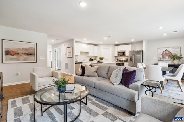 living room featuring baseboards, recessed lighting, light wood-type flooring, and visible vents