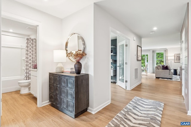 hallway with baseboards, light wood finished floors, and recessed lighting