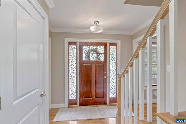 foyer entrance with light wood-style floors, healthy amount of natural light, stairway, ornamental molding, and baseboards