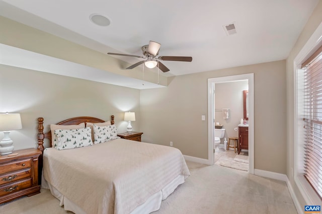bedroom featuring light colored carpet, baseboards, connected bathroom, and ceiling fan