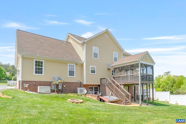 back of property with an outdoor fire pit, stairway, a wooden deck, a sunroom, and roof with shingles
