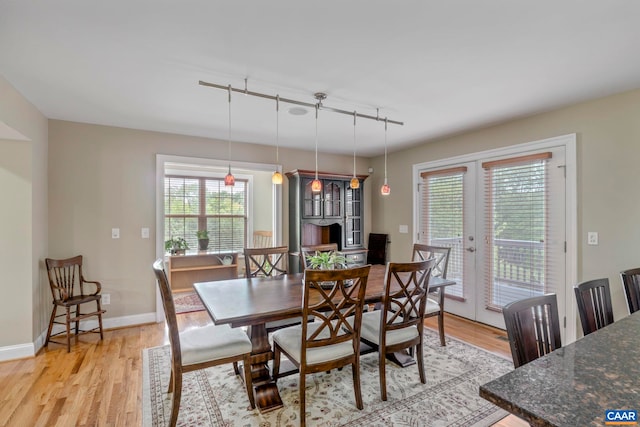 dining area featuring rail lighting, french doors, light wood-style flooring, and plenty of natural light