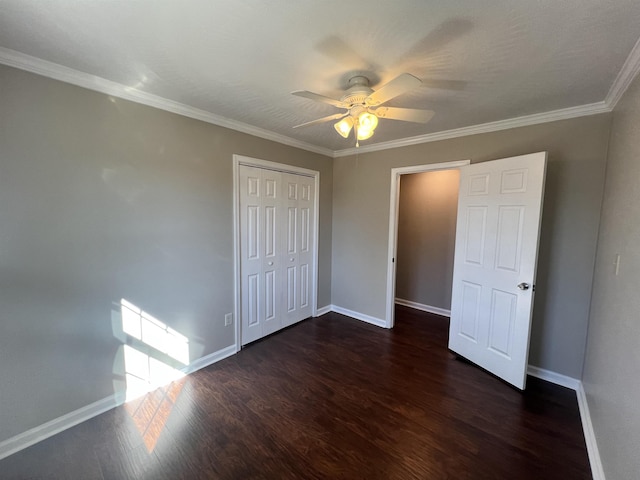 unfurnished bedroom with crown molding, ceiling fan, dark hardwood / wood-style floors, and a closet