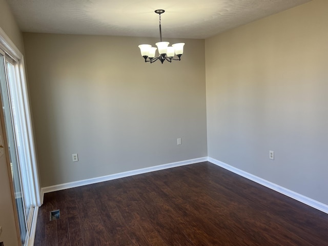 unfurnished room with an inviting chandelier and dark hardwood / wood-style floors