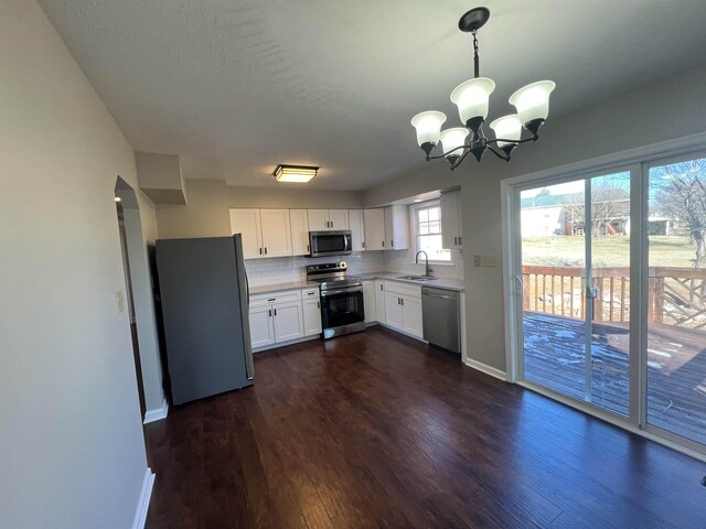 kitchen with decorative light fixtures, white cabinetry, sink, decorative backsplash, and stainless steel appliances