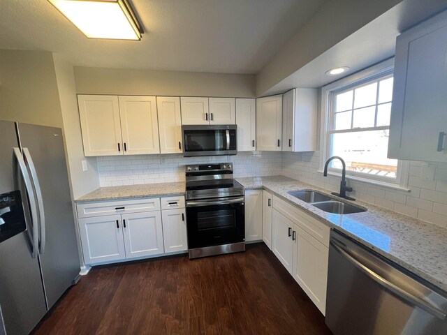 kitchen featuring sink, stainless steel appliances, dark hardwood / wood-style floors, light stone counters, and white cabinets