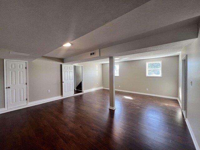 basement featuring dark wood-type flooring and a textured ceiling