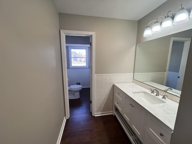 bathroom featuring tile walls, hardwood / wood-style floors, vanity, a textured ceiling, and toilet