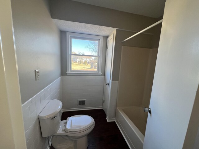 bathroom featuring tile walls and toilet