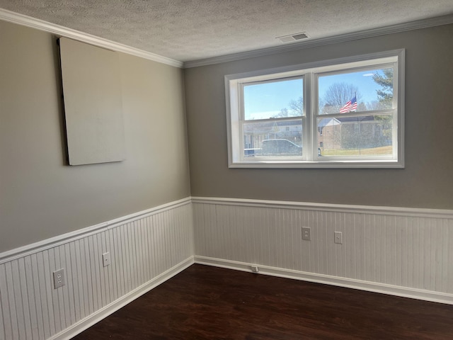 spare room featuring a textured ceiling, dark wood-type flooring, ornamental molding, and a healthy amount of sunlight