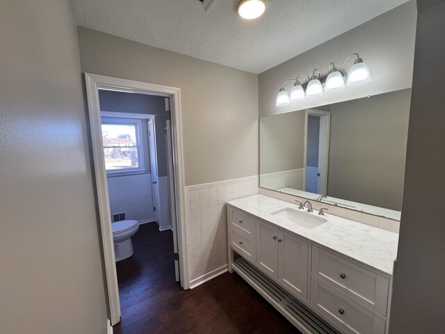 bathroom featuring toilet, wood-type flooring, tile walls, a textured ceiling, and vanity