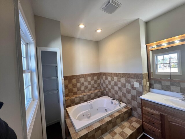 bathroom featuring vanity and a relaxing tiled tub