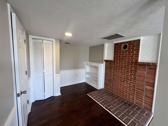 unfurnished living room featuring dark hardwood / wood-style floors and a textured ceiling