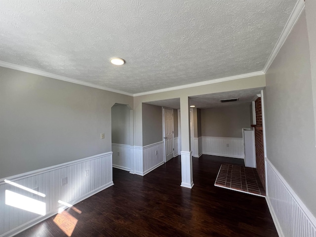 empty room featuring dark wood-type flooring, ornamental molding, and a textured ceiling