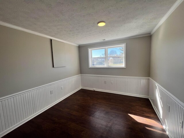 spare room with dark wood-type flooring, ornamental molding, and a textured ceiling