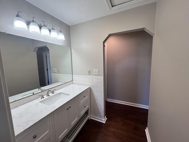 bathroom with hardwood / wood-style flooring, vanity, and tile walls