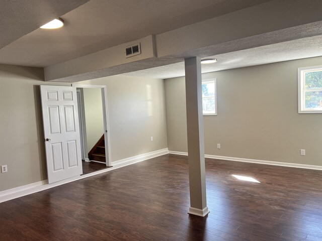 basement featuring a textured ceiling and dark hardwood / wood-style flooring