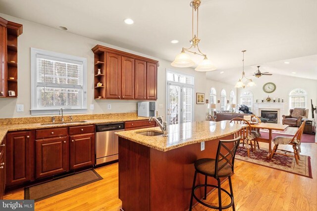 kitchen with sink, stainless steel dishwasher, a kitchen bar, and hanging light fixtures